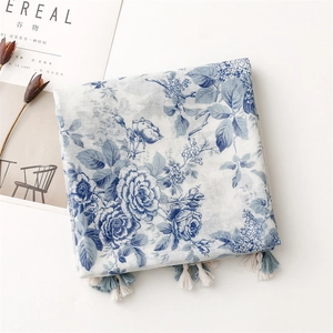 Détail de l'imprimé floral bleu sur écharpe en lin avec pompons bicolores élégants