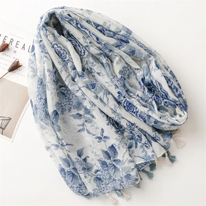 Écharpe longue en coton et lin à fleurs bleues avec pompons sur fond minimaliste