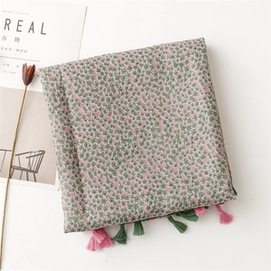 Detail of floral linen scarf with green and pink tassels and elegant flower pattern