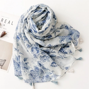 Détail du motif floral à l'encre bleue et franges bicolores sur l'écharpe en lin