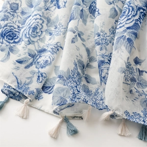 Détail de l'imprimé floral à l'encre bleue sur une écharpe aspect lin avec des franges