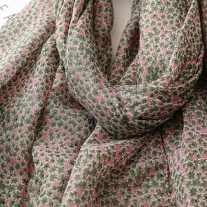 Detailed close-up of floral cotton-linen scarf with pink and dark green patterns