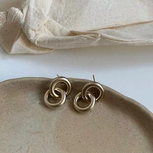 Boucles d'oreilles géométriques dorées mates à double anneau sur un plateau céramique