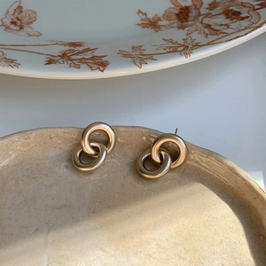 Boucles d'oreilles doubles anneaux dorés mats sur un plateau en céramique texturé