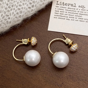 Close-up of vintage gold C-shaped earrings with micro-pave zircons and large white pearls