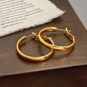 Close-up of polished gold hoop earrings on a vintage wood background