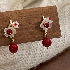 Detail of vintage flower earrings with white petals and red round pearl pendants