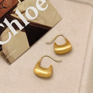 Minimalistische mattgoldene Halbmond-Ohrringe mit gebürstetem Metall auf Sandboden