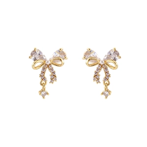 Elegant gold bow earrings with shimmering zircons and white pearls on white background
