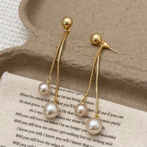 Detail of elegant gold drop earrings featuring pearl tassels on sleek snake chains