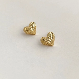 Elegant gold heart stud earrings with quilted metallic texture on a neutral background
