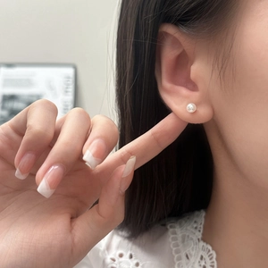 Gros plan d'une élégante boucle d'oreille puce en perle blanche de 8mm portée