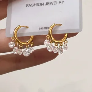 Macro shot of gold hoop earrings with five hanging cubic zirconia stones and S925 silver pins