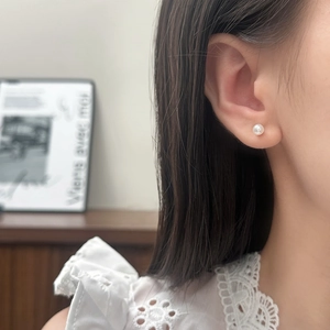 Gros plan de boucles d'oreilles perles blanches minimalistes portées par un mannequin