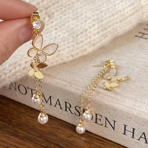 Detailed macro of golden butterfly tassel earrings with pearls and zircon stones