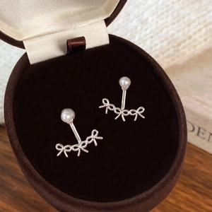 Élégantes boucles d'oreilles nœud en argent avec perle blanche dans un écrin en velours