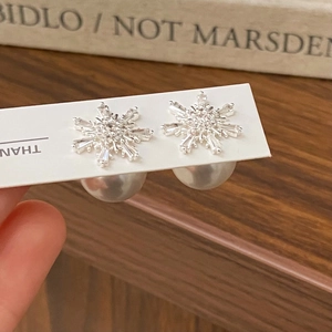 Détail de boucles d'oreilles flocon avec zircone et fermoir perle blanche amovible