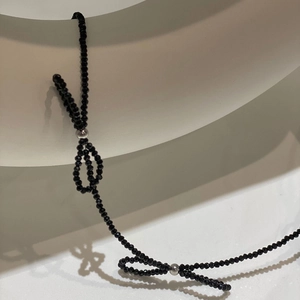 Detail of beaded necklace featuring black faceted crystals and elegant bow accents