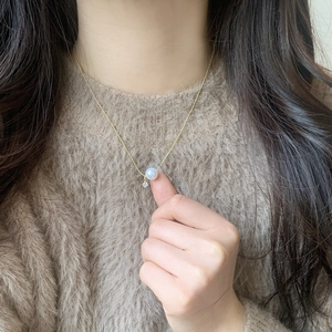 Minimalist gold pearl necklace with zircon accent on model wearing brown sweater