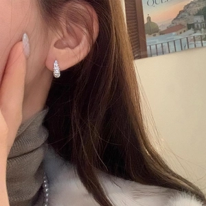 Detailed view of silver pavé cubic zirconia hoop earrings worn with elegant outfit