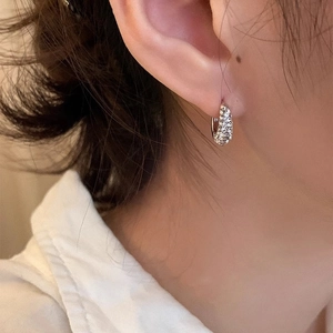 Sparkling zircon paved silver hoop earrings shown on model ear for an elegant look
