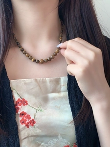 Detailed view of natural tiger eye stone beaded necklace worn with vintage embroidery