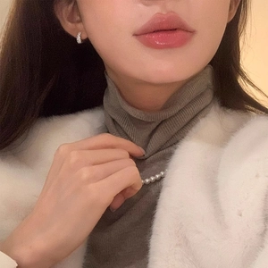 Close-up of luxury micro-pave zircon hoop earrings and elegant pearl necklace on a model