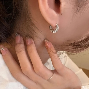 Close-up of silver hoop earrings paved with sparkling cubic zirconia on a model