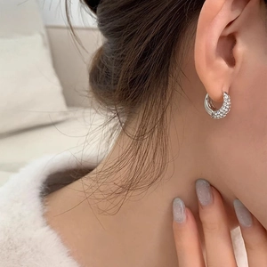 Close-up of sparkling zircon hoop earrings showing refined metal craftsmanship on ear