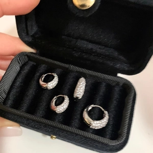 Close-up of four silver hoop earrings with pavé zircons in a black velvet jewelry box