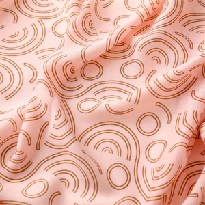 Detailed texture of pink cotton linen scarf featuring brown geometric circle patterns