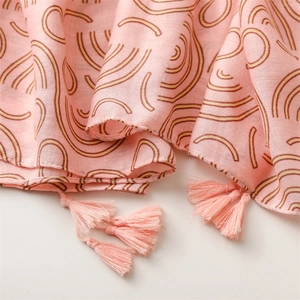 Close-up of pink linen scarf with soft rainbow prints and delicate fringe tassels