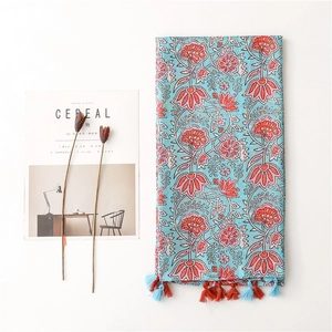 Blue linen scarf with coral floral patterns and colorful tassels on white background