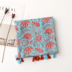 Detail of light blue floral cotton scarf with orange water lily prints and tassels