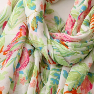 Close-up of tropical parrot and palm leaf prints on cotton linen twill scarf fabric