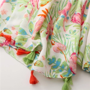 Detail of floral bird print scarf featuring vibrant tassels and cotton linen texture