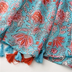 Close-up of sky blue linen scarf with orange floral prints and colorful tassel edges
