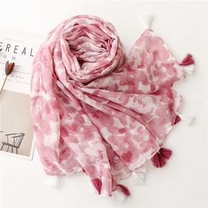 Détail d'une écharpe en coton à fleurs roses avec des glands bordeaux et des franges