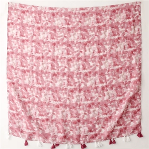 Détail du châle à imprimé floral rose avec pompons doux et texture semi-transparente