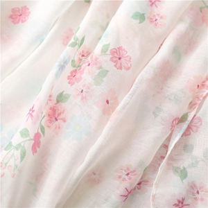 Close-up of lightweight floral scarf fabric showing soft cotton linen texture and tassels