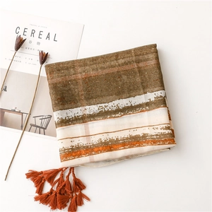 Flat lay of earth-toned striped scarf with orange tassels and bohemian vintage texture