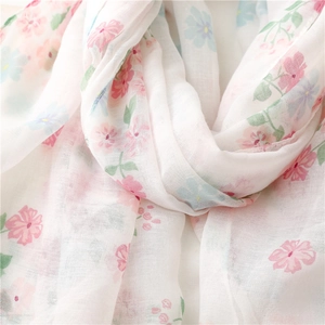 Close-up of white floral scarf with pink and blue blossoms and soft woven texture