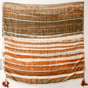 Detail of bohemian scarf with orange tassels and artistic striped pattern on fabric