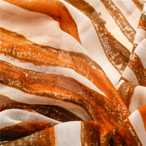 Detail of bohemian scarf featuring colorful stripes, gold foil threads and soft fabric texture