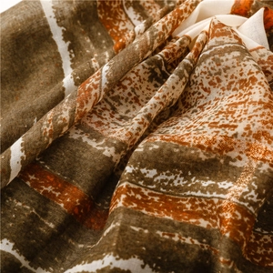 Detail of bohemian scarf featuring metallic threads and artistic orange stripe patterns