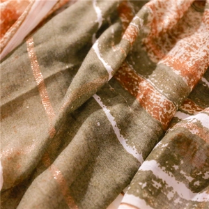 Macro detail of Bohemian scarf featuring metallic bronze stripes and woven fringe texture