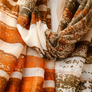 Detailed close-up of striped sun protection shawl with golden silk thread and tassels