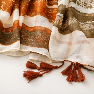 Detailed view of bohemian shawl with metallic gold threads and orange tassels
