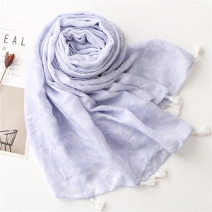 Close-up of lavender floral beach shawl with white tassels and wrinkled linen texture