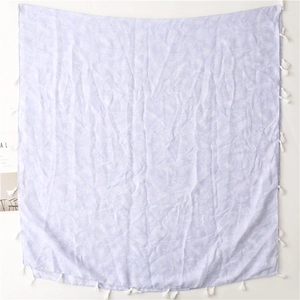 Macro detail of a light purple scarf featuring white floral prints and fringe edges